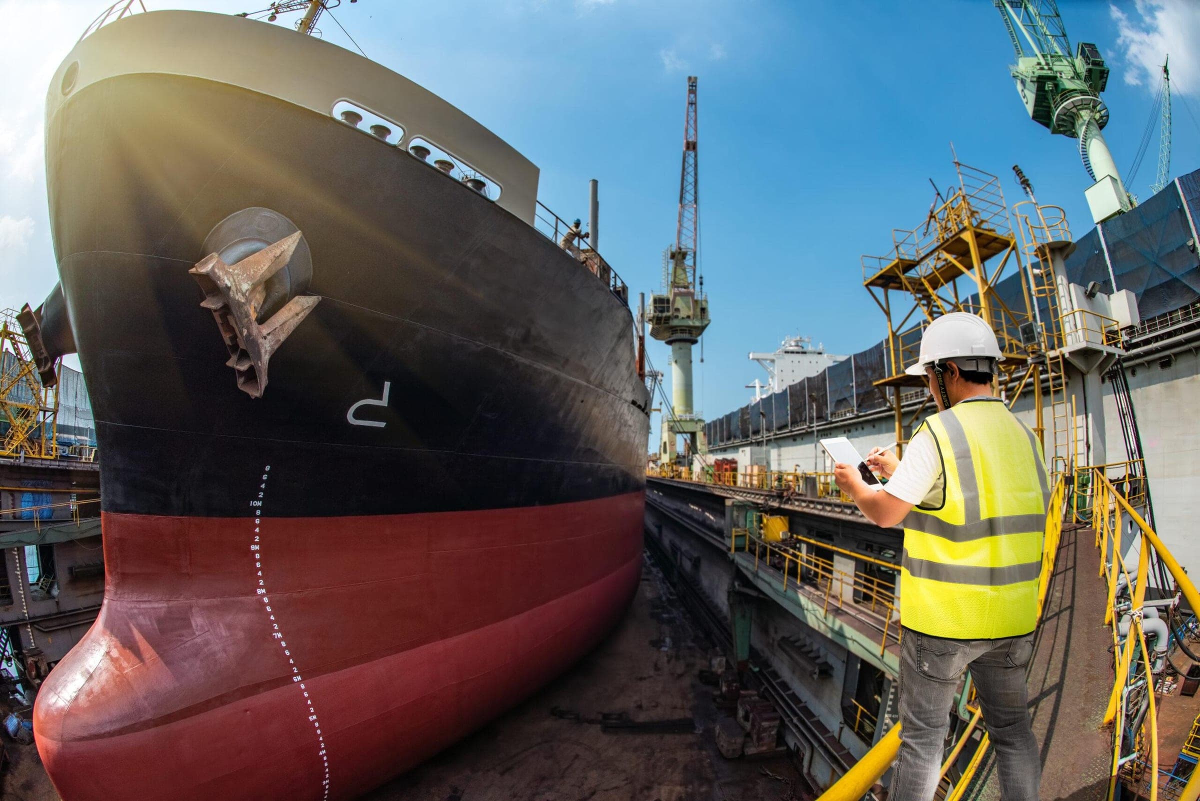 Surveyor recording findings beside a vessel in dry dock