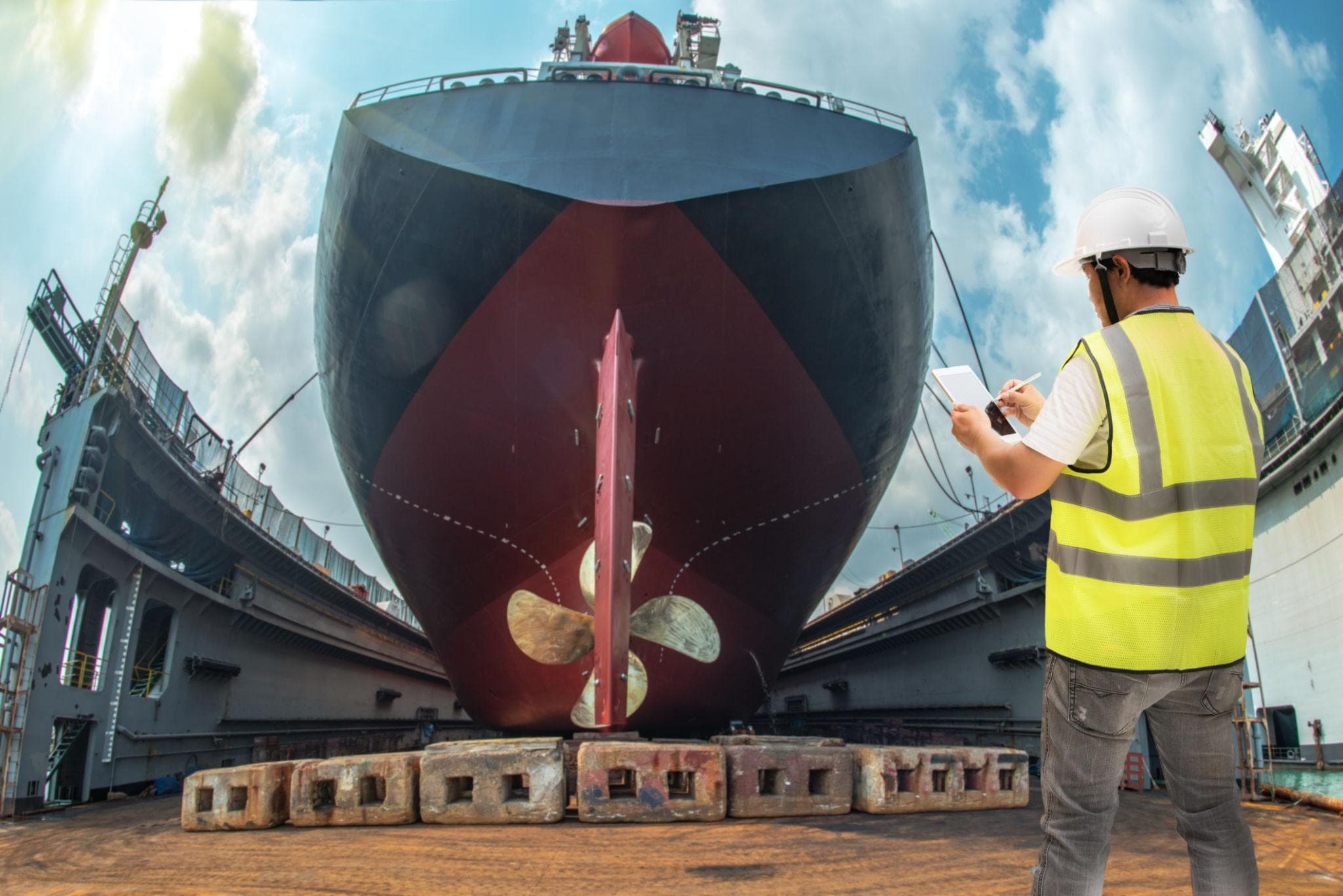 Surveyor at the stern of a vessel raised in dry dock