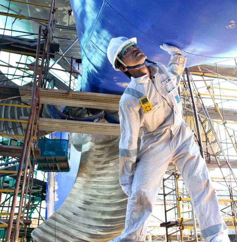 Surveyor inspecting a hull supported in dry dock